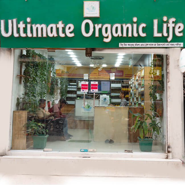 Ultimate Organic Life Gazipur Branch storefront exterior, located in Nidu Mia Complex at Board Bazar, showing green plants and the organic health food store interior